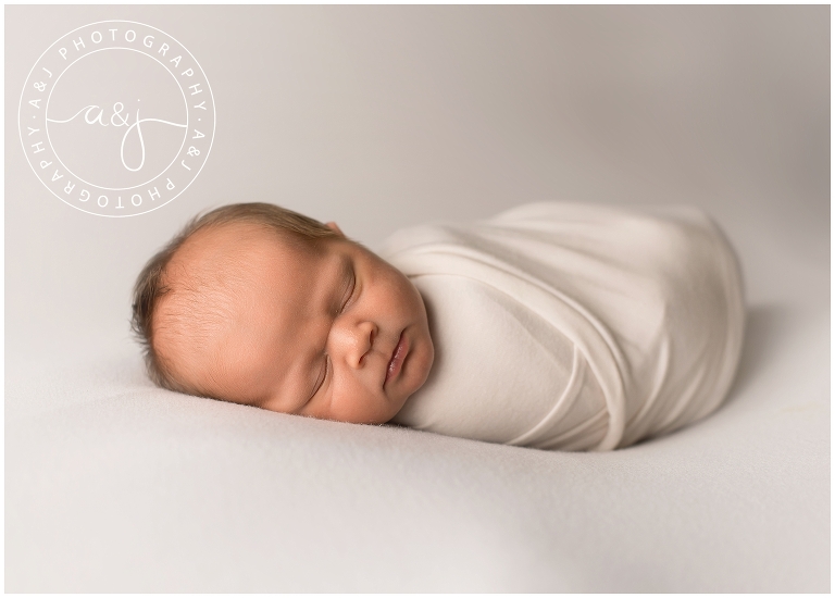newborn boy swaddled in white pose